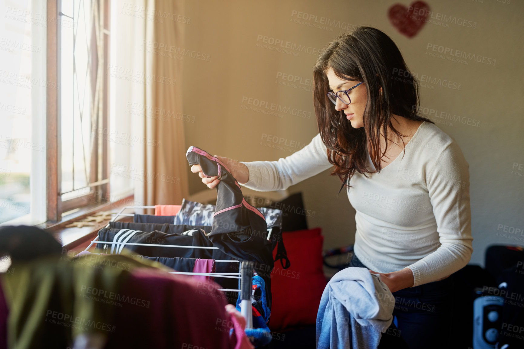 Buy stock photo Cropped shot of a young woman hanging up some laundry at home