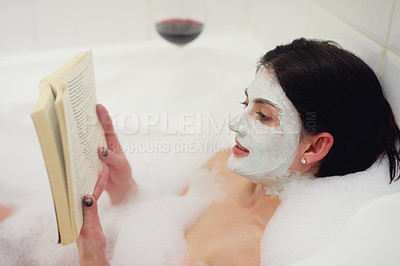 Buy stock photo Cropped shot of a young woman relaxing in the bathtub with a book and glass of wine