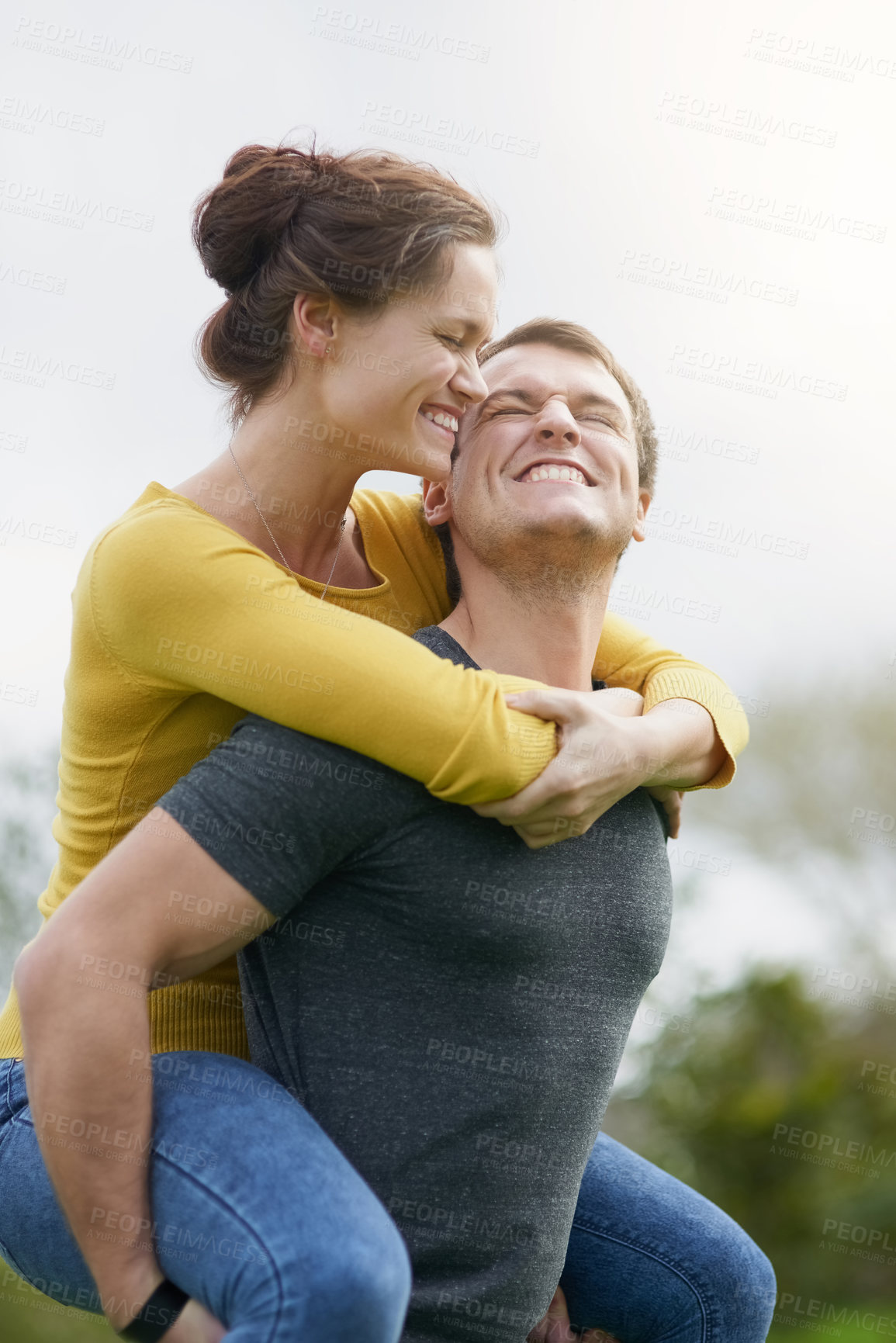 Buy stock photo Shot of a happy man giving his wife a piggyback ride outside