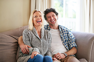 Buy stock photo Shot of a mature couple laughing while relaxing on their sofa at home