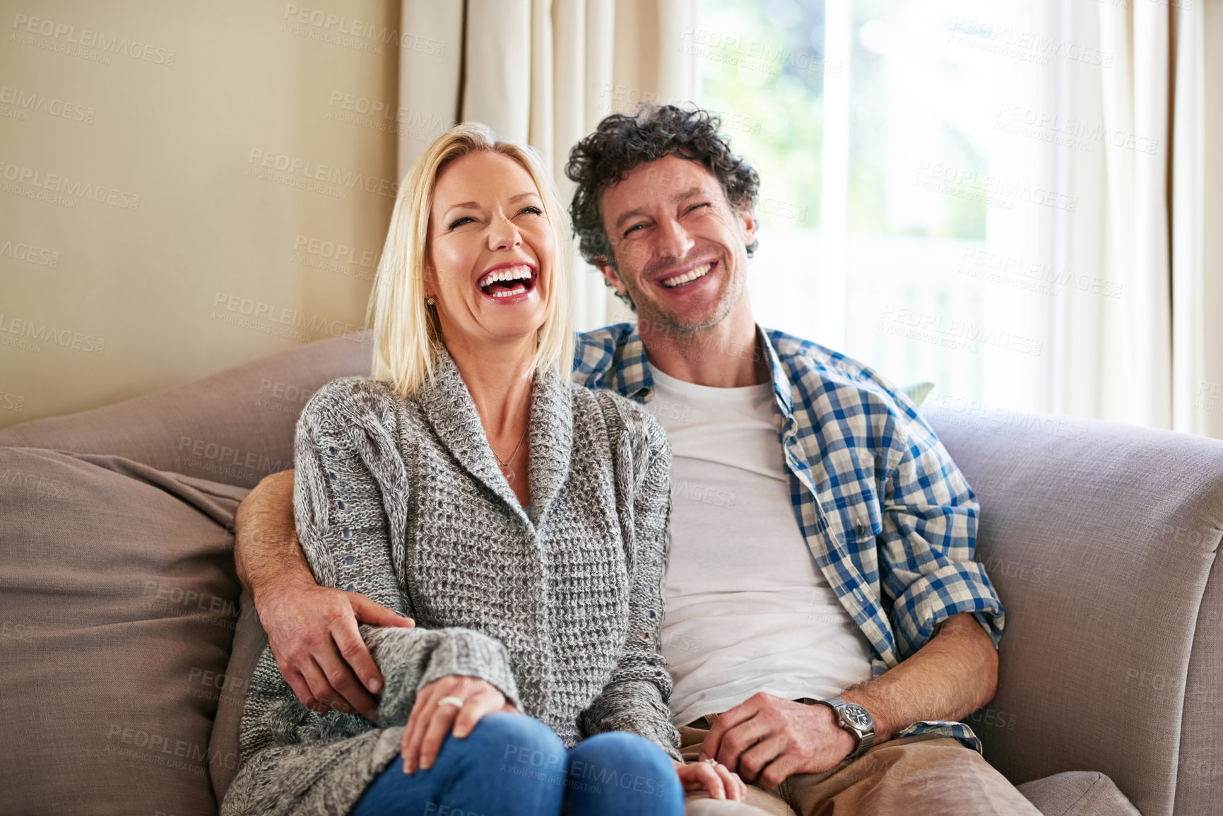 Buy stock photo Shot of a mature couple laughing while relaxing on their sofa at home