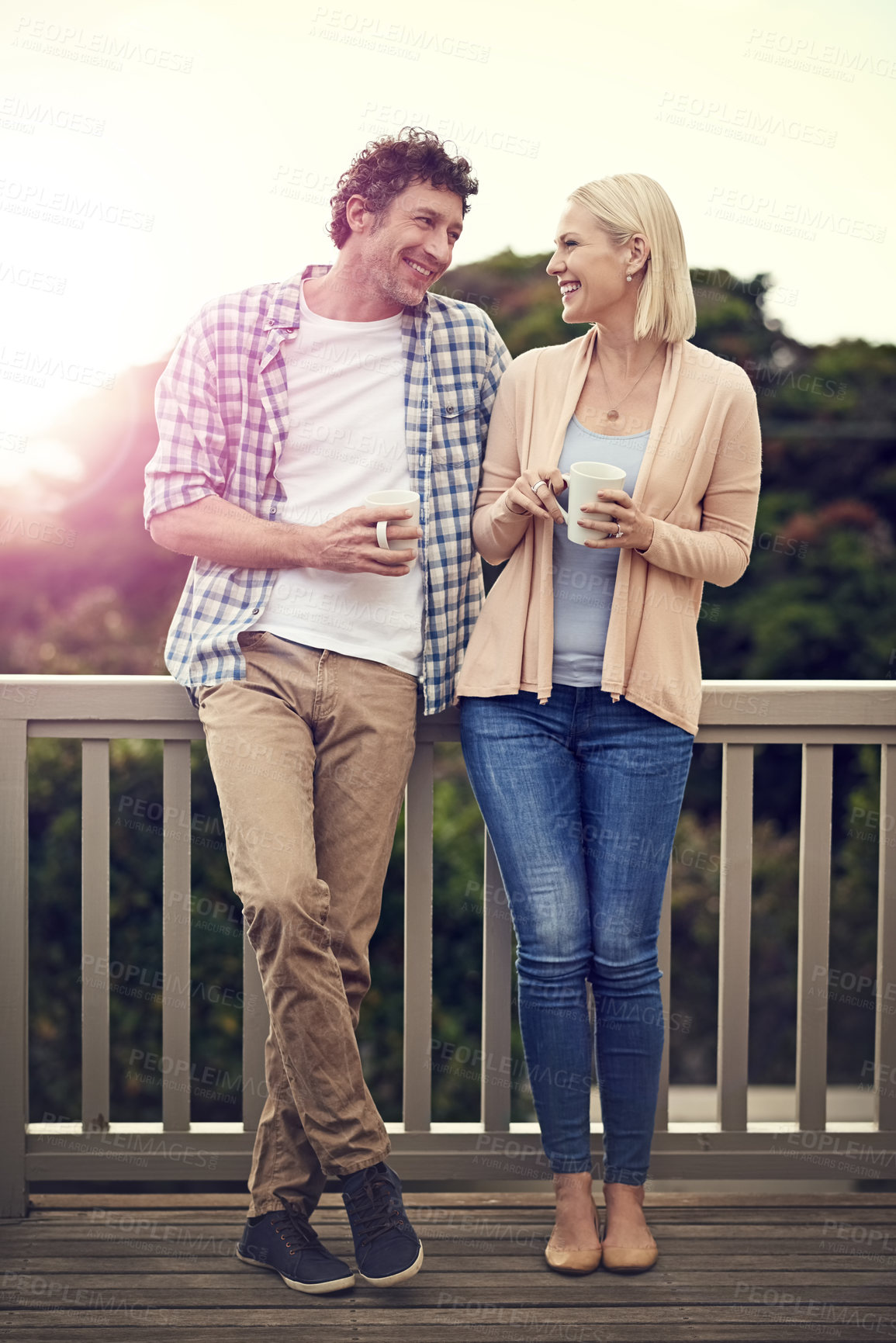 Buy stock photo Shot of a happy couple drinking coffee on their balcony together