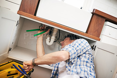 Buy stock photo Shot of a man fixing a pipe under his kitchen sink