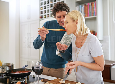 Buy stock photo Shot of a happy couple cooking dinner together in their kitchen