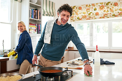 Buy stock photo Shot of a happy couple cleaning their kitchen together after cooking dinner