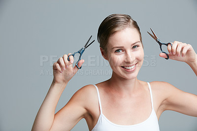 Buy stock photo Studio portrait of an attractive young woman holding scissors against a gray background