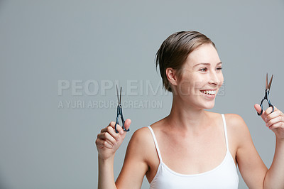 Buy stock photo Studio shot of an attractive young woman holding scissors against a gray background