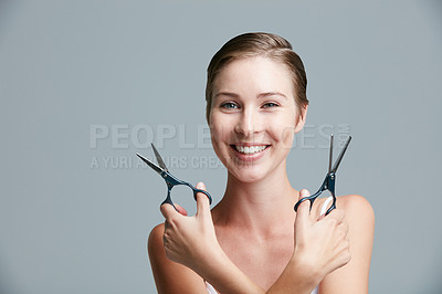 Buy stock photo Studio portrait of an attractive young woman holding scissors against a gray background