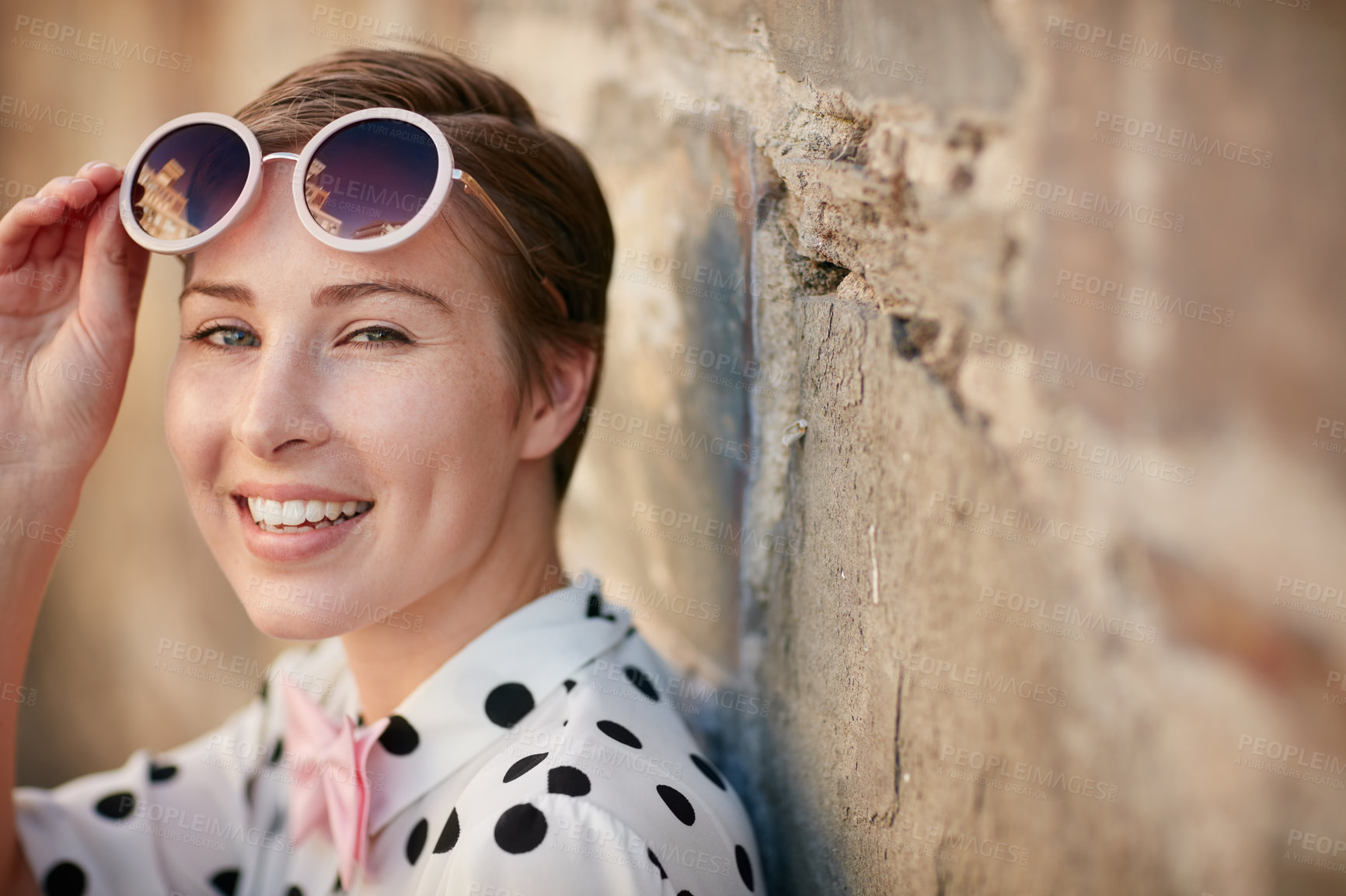 Buy stock photo Portrait of a trendy young woman leaning against a brick wall outside