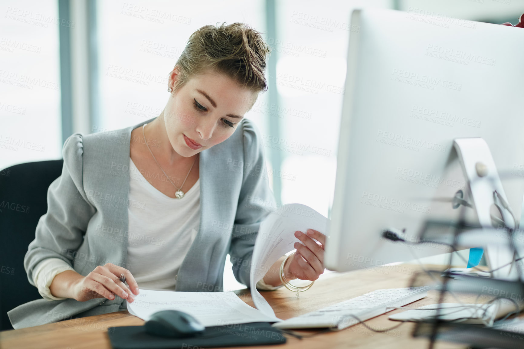 Buy stock photo Cropped shot of a young businesswoman reading some paperwork in an office