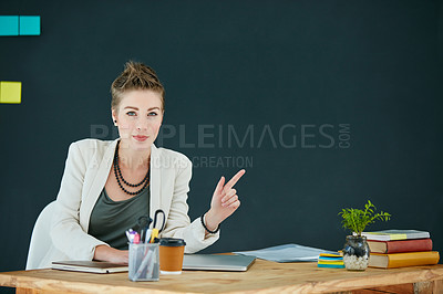 Buy stock photo Portrait of a young businesswoman pointing at something in an office