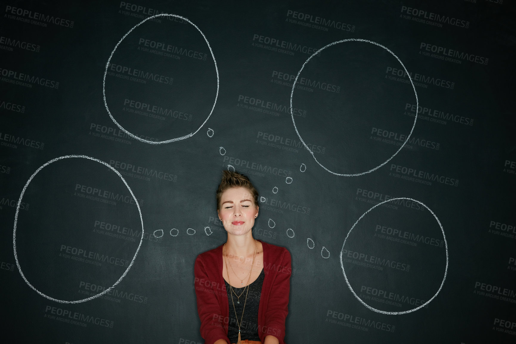 Buy stock photo Studio shot of a young woman posing with a chalk illustration of thought bubbles against a dark background