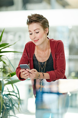 Buy stock photo Shot of an attractive young businesswoman using her cellphone in the office