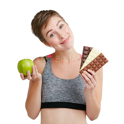 Buy stock photo Studio portrait of a fit young woman deciding whether to eat chocolate or an apple against a white background
