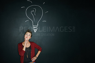 Buy stock photo Studio shot of a young woman posing with a chalk illustration of a lightbulb against a dark background