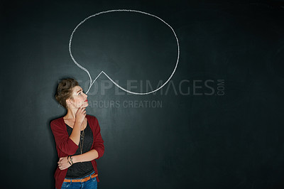 Buy stock photo Studio shot of a young woman posing with a chalk illustration of a speech bubble against a dark background
