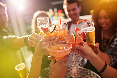 Buy stock photo Shot of a group of people toasting with their drinks at a nightclub