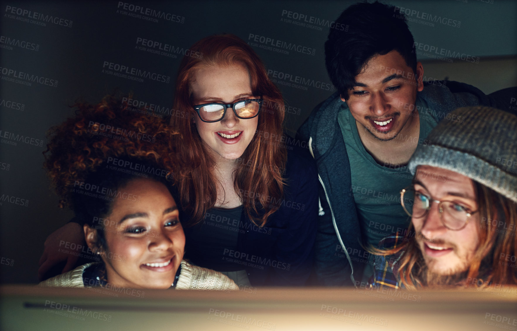 Buy stock photo Shot of a business team looking at a computer screen on a night shift at the office