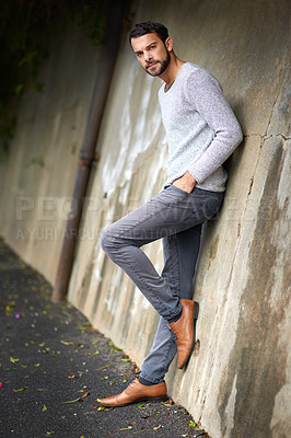 Buy stock photo Shot of a handsome young man posing against an urban wall