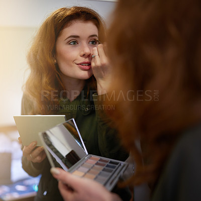 Buy stock photo Shot of an attractive young woman applying makeup in the mirror