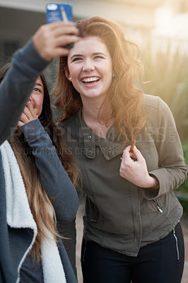 Buy stock photo Shot of two young women taking a selfie outdoors