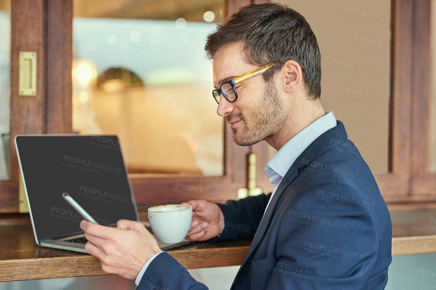 Buy stock photo Shot of a young businessman sending a text message while sitting in a coffee shop