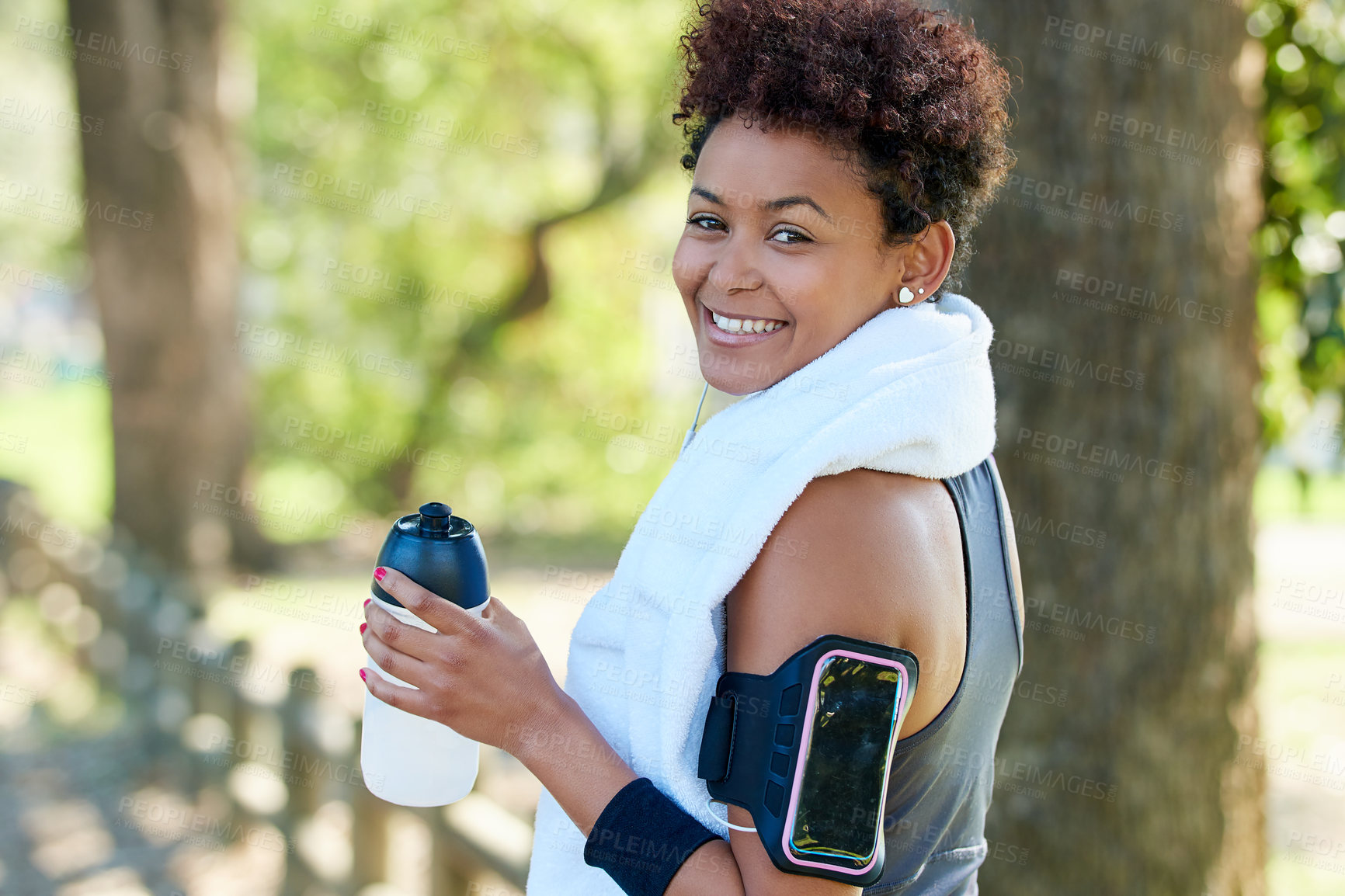 Buy stock photo Portrait, woman and run with water bottle, outdoor and exercise for fitness, training and wellness. Female athlete, armband and nature in hydration, physical sports and smile in forest with towel 