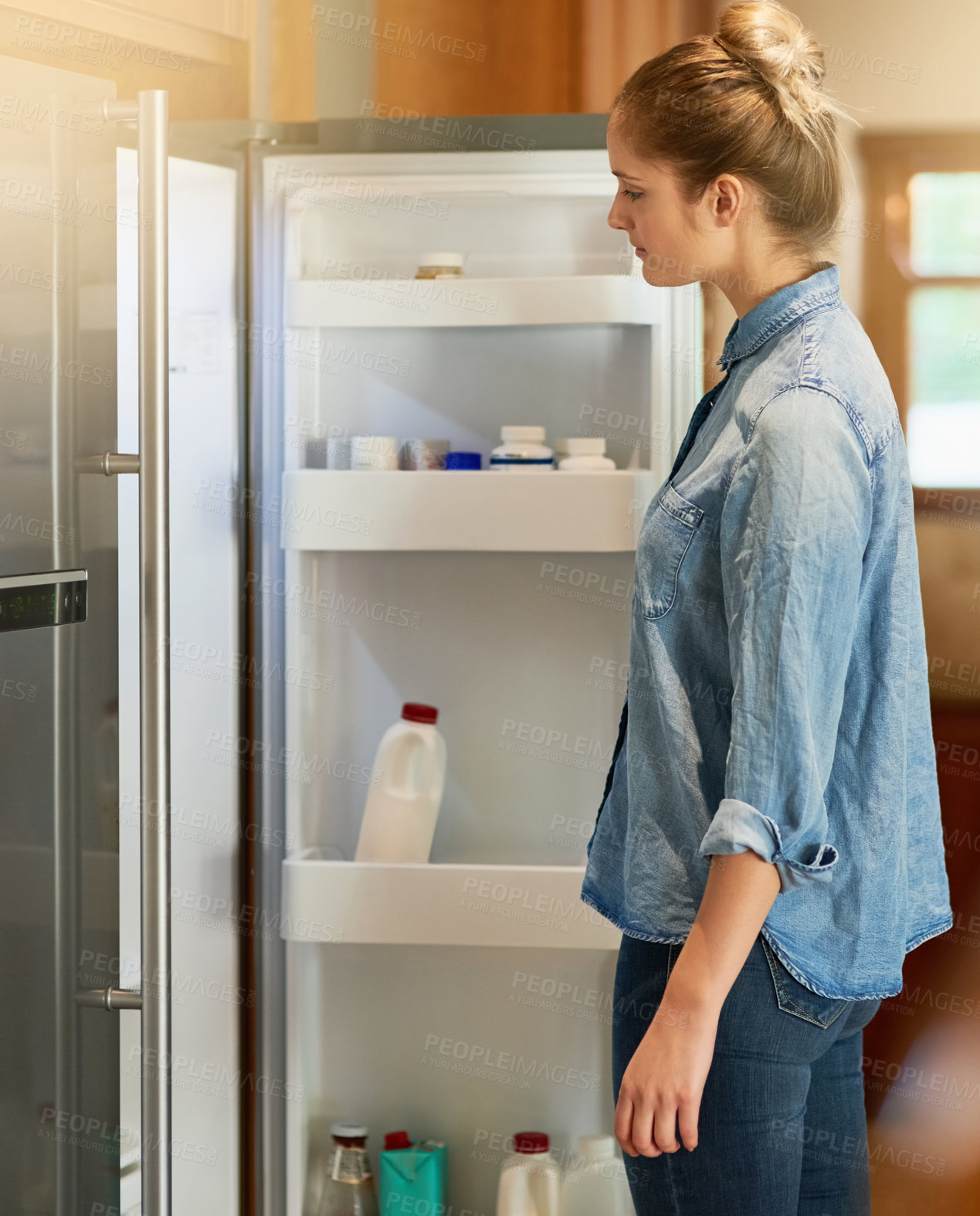 Buy stock photo Cropped shot of a young woman looking inside her fridge at home
