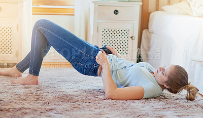 Buy stock photo Shot of a young woman struggling to fit into her jeans at home
