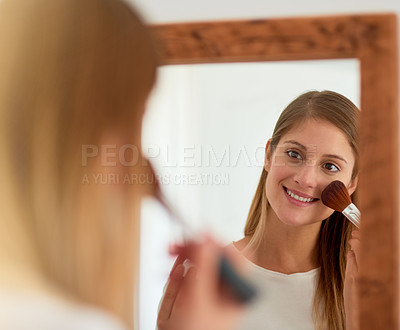 Buy stock photo Shot of a young woman applying blusher in front of a mirror at home