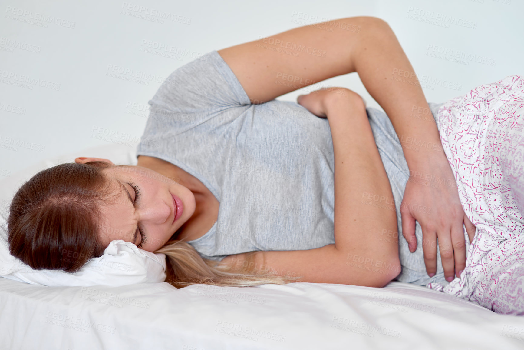 Buy stock photo Home, woman and lying in bed with stomach pain, menstrual cramps and abdominal ache. House, bedroom and girl with medical crisis, appendicitis and gastritis with discomfort of inflammation indoor