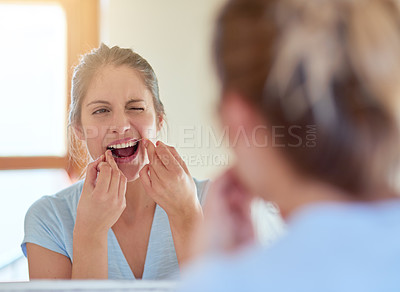 Buy stock photo Cropped shot of a young woman flossing her teeth in a mirror