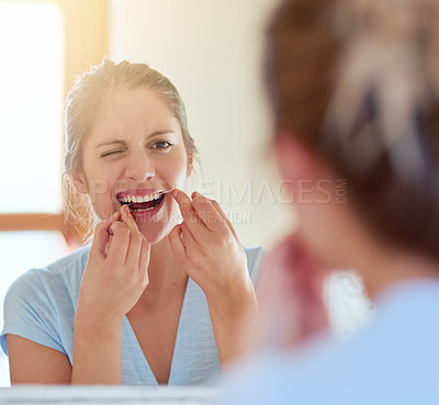 Buy stock photo Cropped shot of a young woman flossing her teeth in a mirror