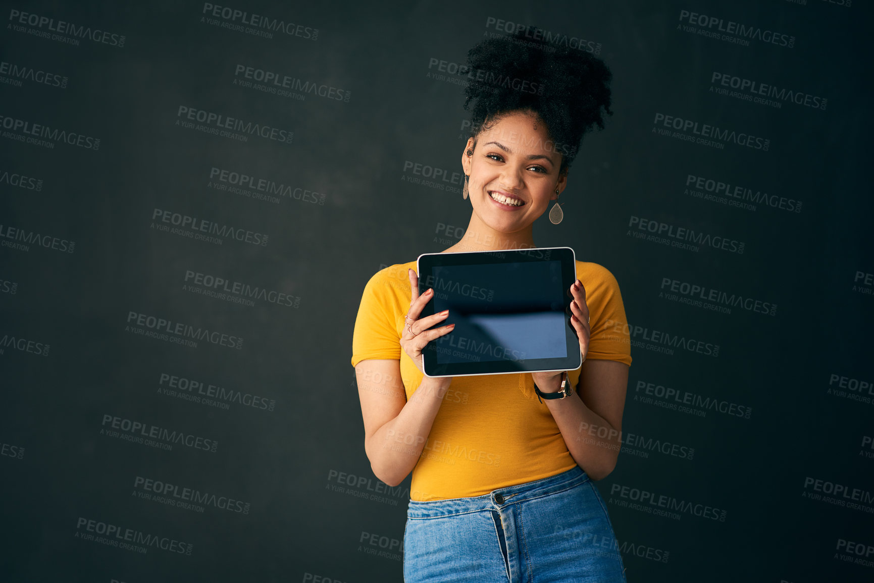 Buy stock photo Shot of a young woman holding a digital tablet while posing against a grey background
