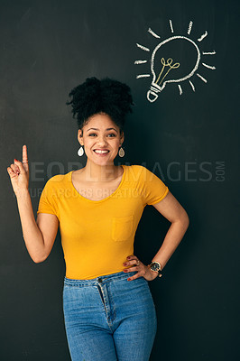 Buy stock photo Shot of a woman posing with a chalk illustration of a lightbulb against a dark background