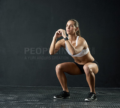 Buy stock photo Studio shot of an attractive young woman doing squats against a dark background