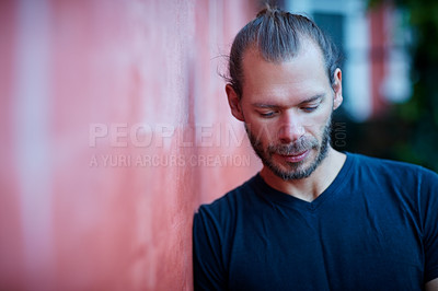 Buy stock photo Shot of a man leaning against a wall outside