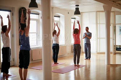 Buy stock photo Shot of a yoga instructor leading his class in a yoga routine