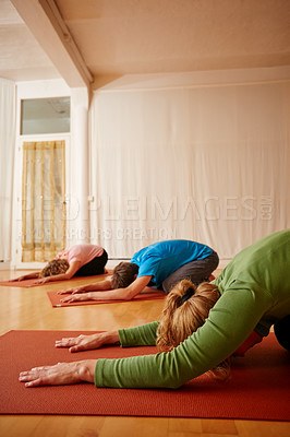 Buy stock photo Shot of three people doing yoga together in a studio