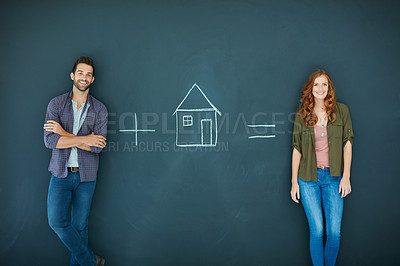 Buy stock photo Shot of a young couple standing in front of a blackboard with symbols written on it