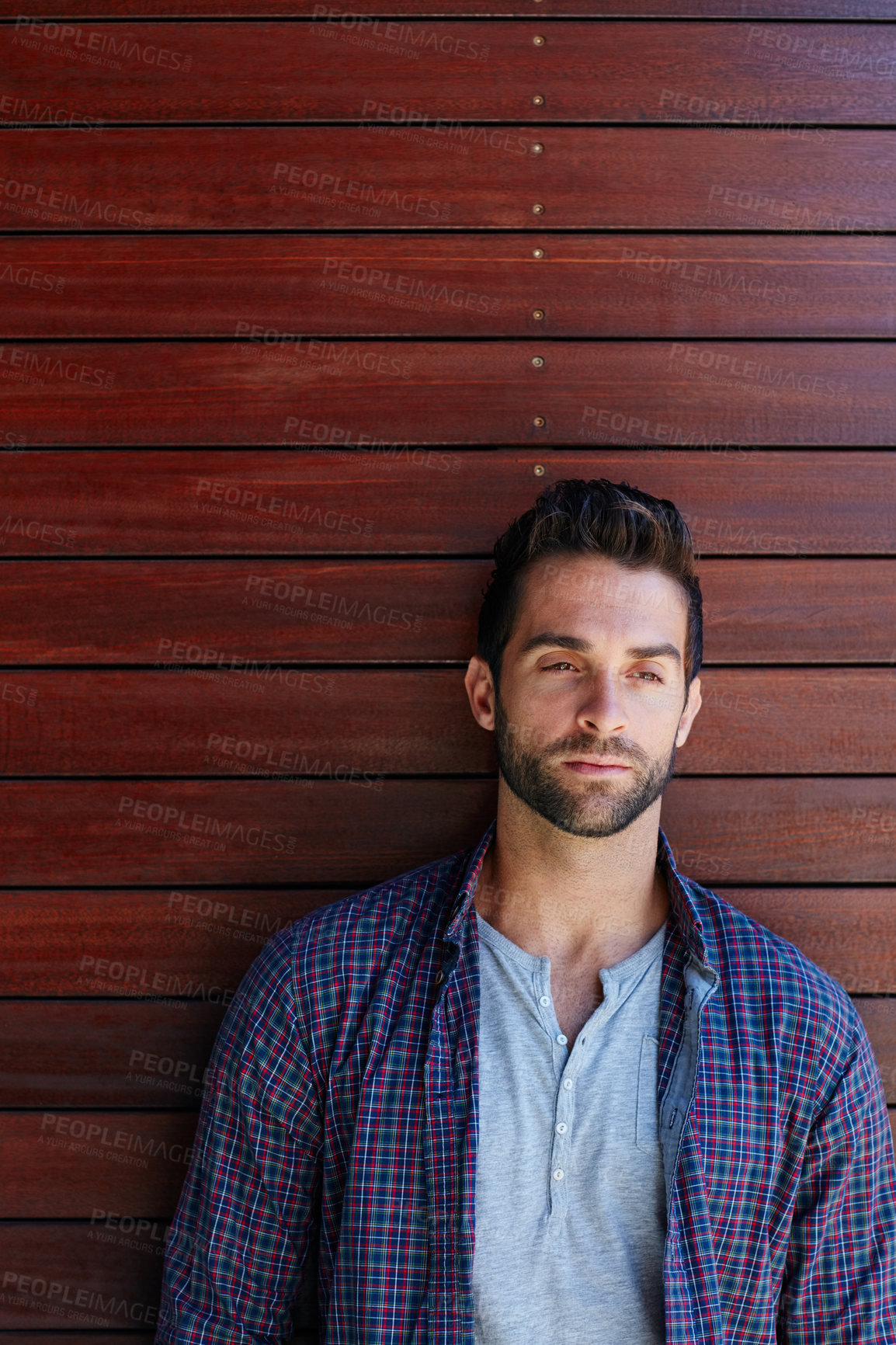 Buy stock photo Shot of a handsome man standing against a wooden wall