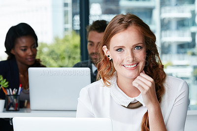 Buy stock photo Portrait of a young businesswoman working in an office with colleagues in the background