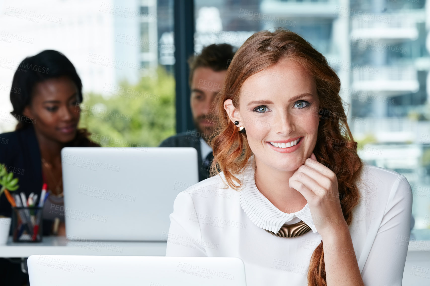 Buy stock photo Portrait of a young businesswoman working in an office with colleagues in the background