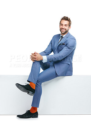 Buy stock photo Studio shot of a handsome businessman sitting on a wall against a white background