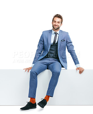 Buy stock photo Studio shot of a handsome businessman sitting on a wall against a white background