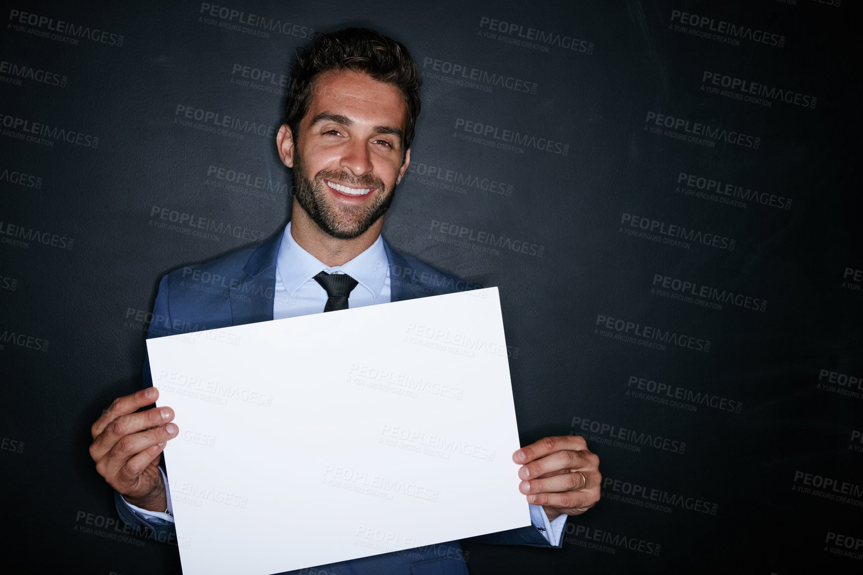 Buy stock photo Studio portrait of a handsome young man holding a blank placard against a dark background