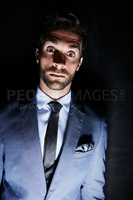 Buy stock photo Studio portrait of an eerie looking young man standing against a dark background
