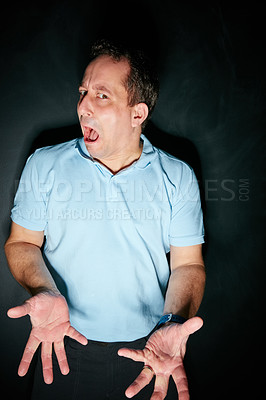 Buy stock photo Studio portrait of an expressive man posing against a dark background
