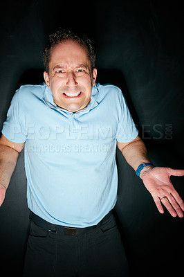 Buy stock photo Studio portrait of an expressive man shrugging his shoulders against a dark background