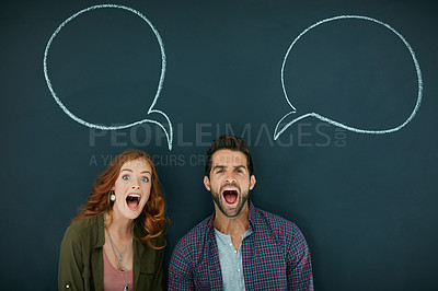 Buy stock photo Portrait of a young couple standing in front of a blackboard with speech bubbles drawn on it